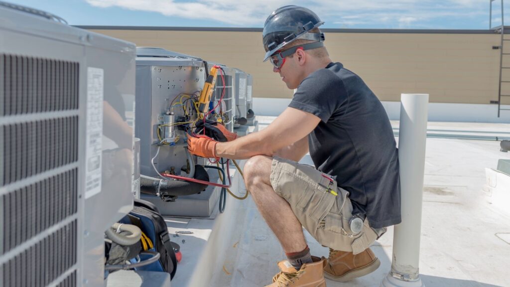 Technician servicing rooftop air-conditioning equipment