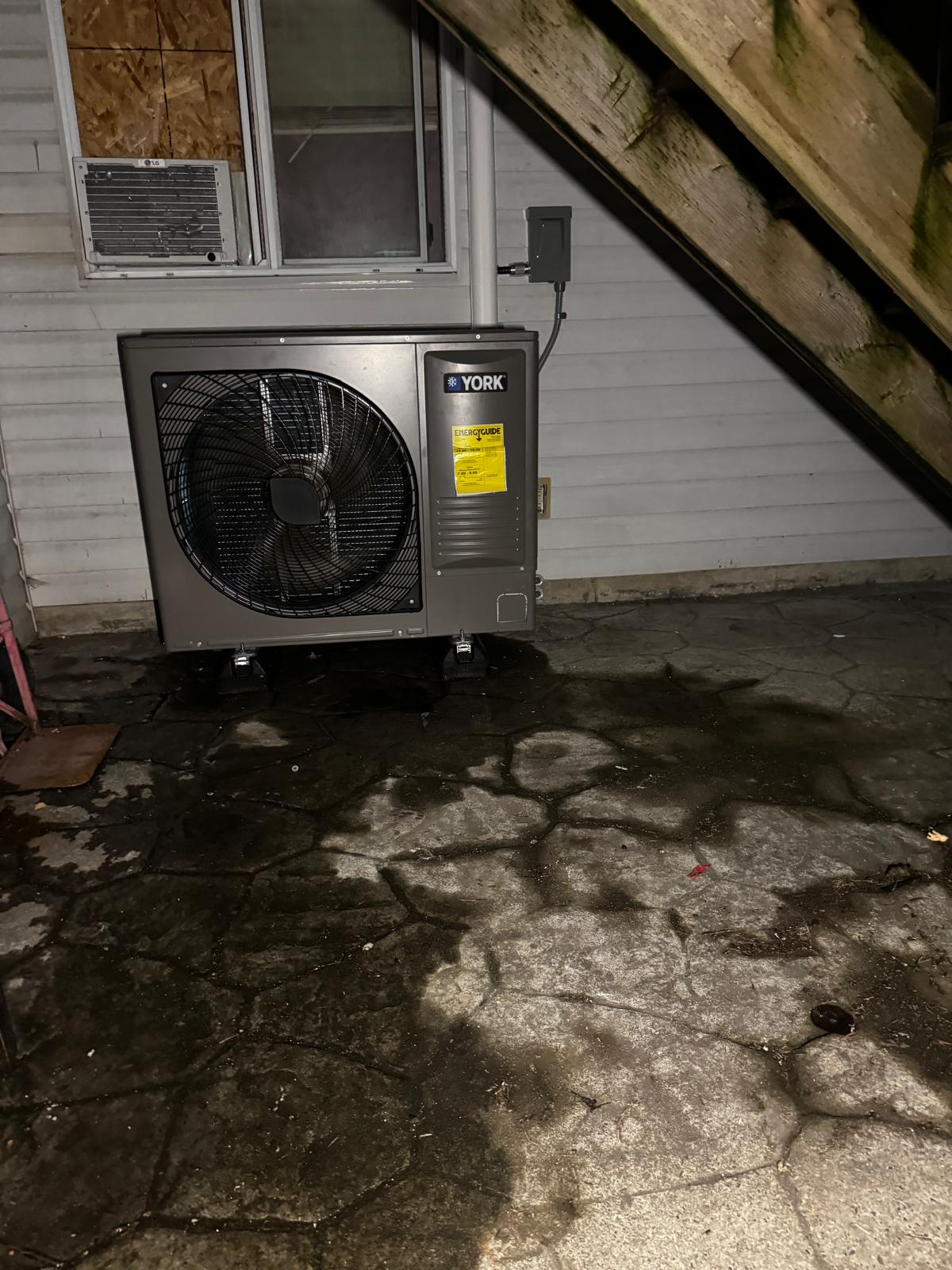 Outdoor heat-pump condenser beside a home